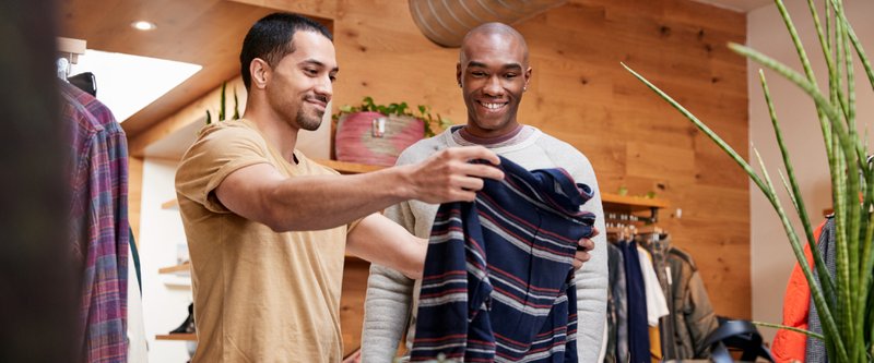 Two smiling men looking at a shirt in a shop