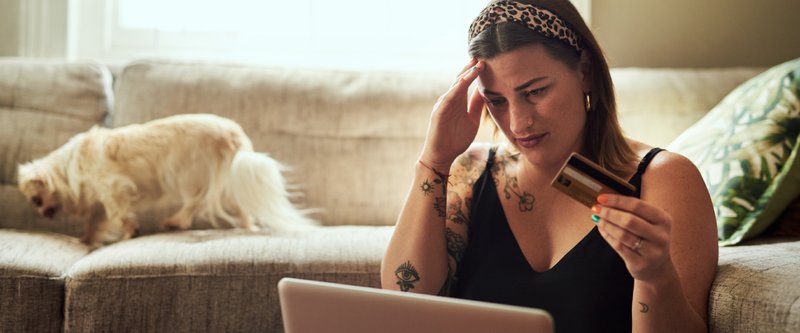 A women staring at her credit card and computer stressed