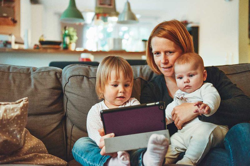 A-mum-and-two-kids-facetiming-someone-on-a-tablet-by-alexander-dummer-on-unsplash.jpg