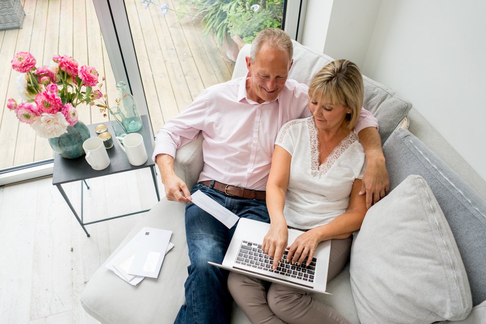 A couple in a living room staring at computer with letters