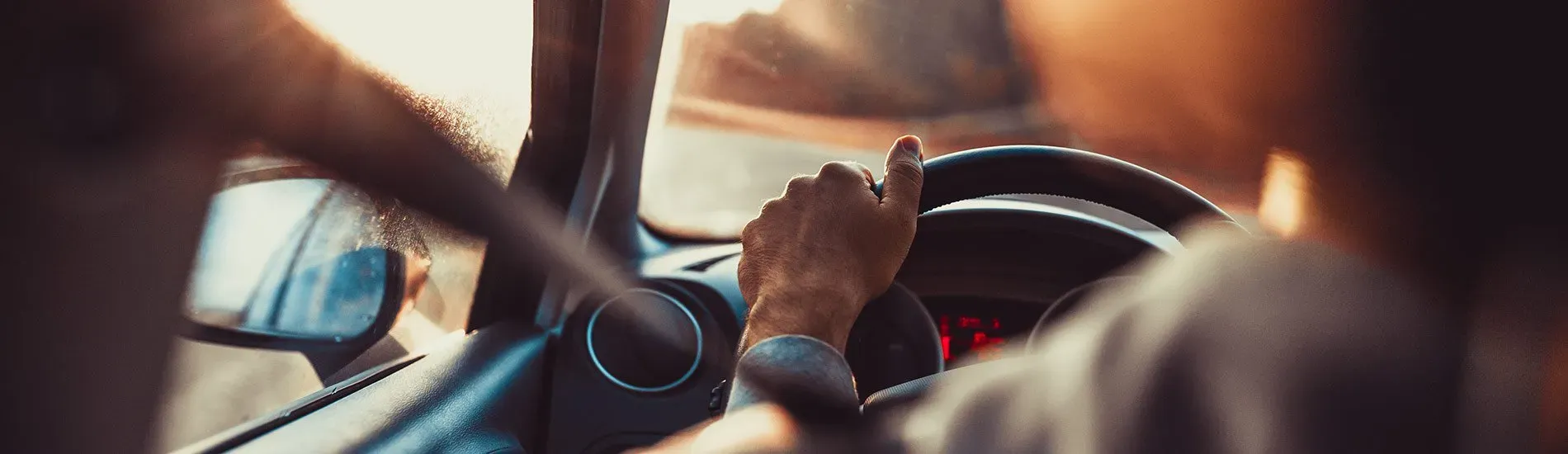 Person with hands on steering wheel driving a car in New Zealand