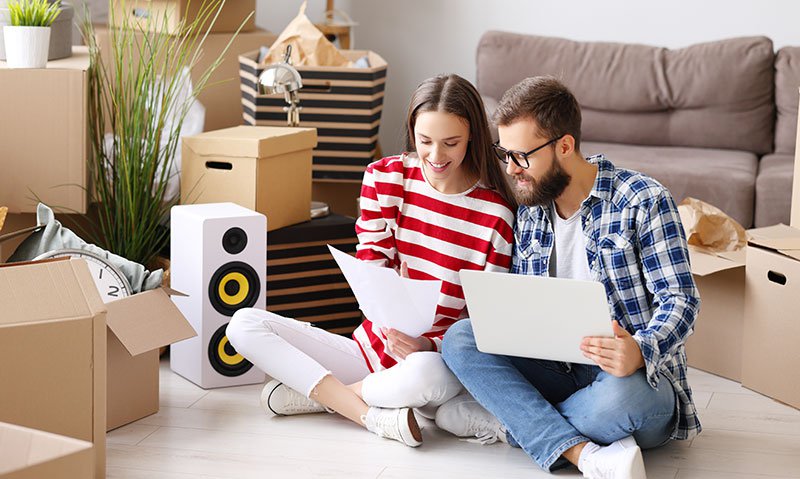 Cheerful couple with laptop discussing insurance of new home