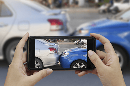 Close up of hands holding smartphone and taking a photo of a car accident damage