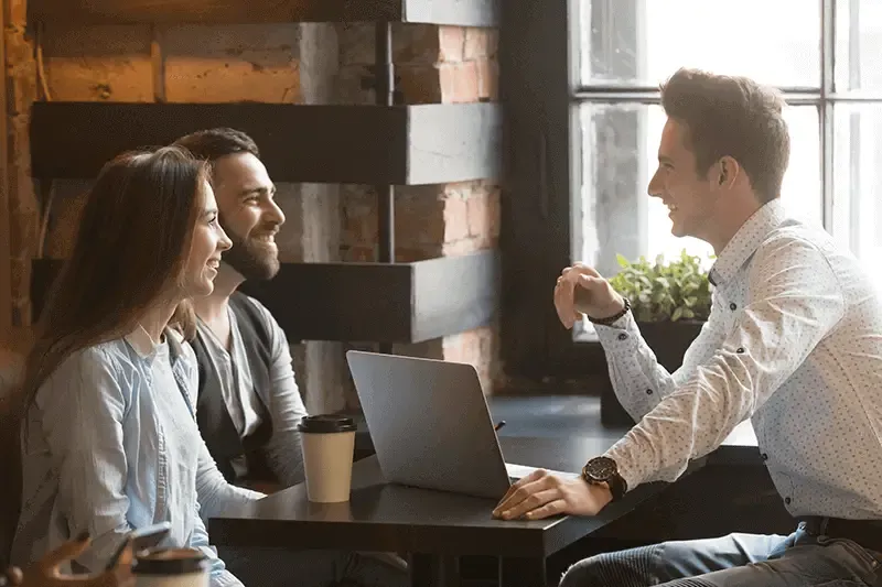 Excited young couple meet with realtor in a coffee shop