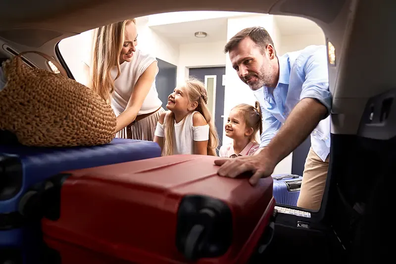 Family packing luggage into a car