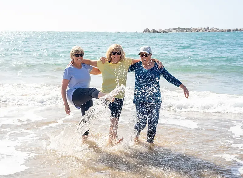 Group of three women walking having fun on beach