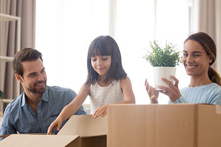 Happy family unpacking moving boxes