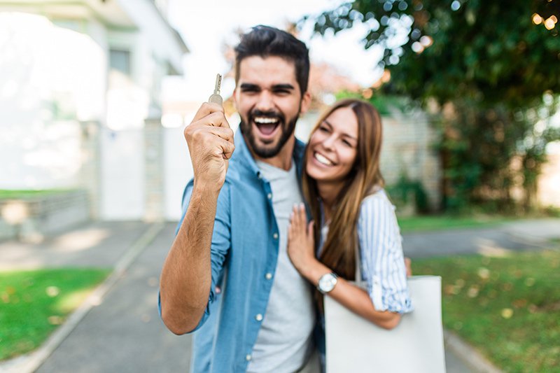 Happy young couple holding the key to a home