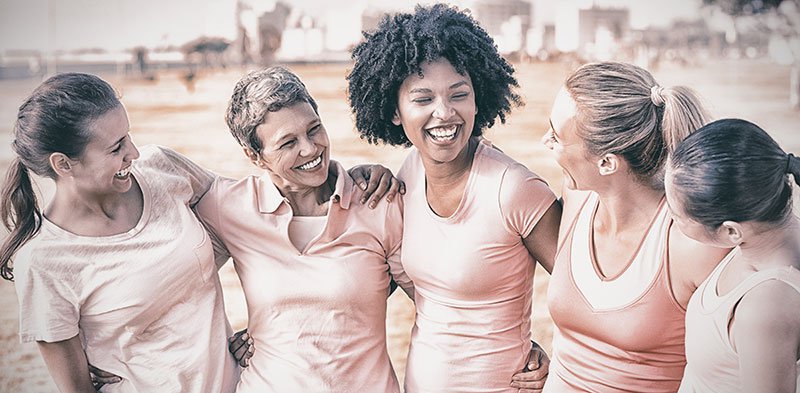 Group of women laughing and wearing pink tshirts for breast cancer awareness