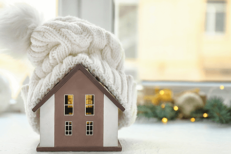 Model of house with white woolen hat on top next to window