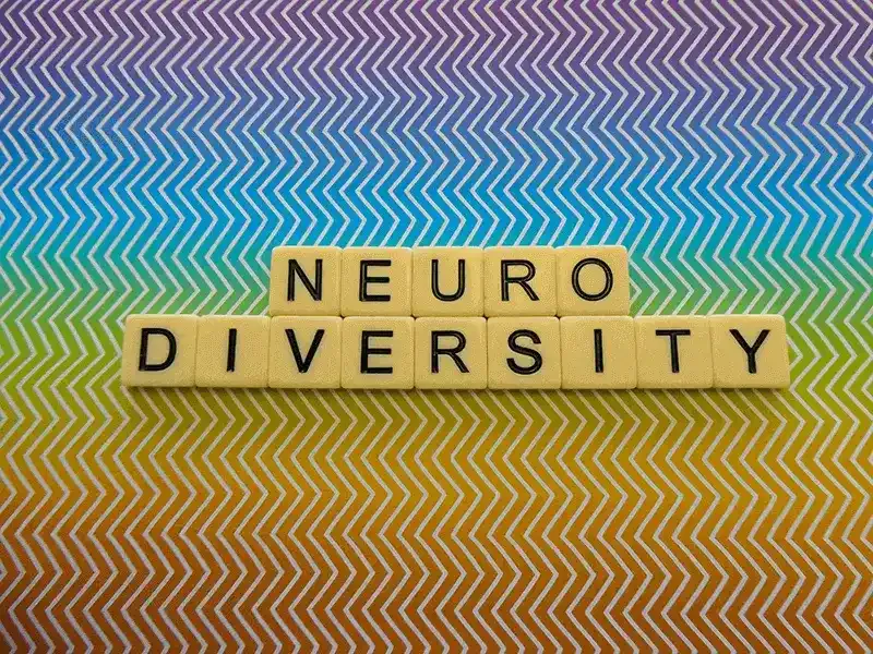 Neurodiversity-spelt-in-scrabble-letters-with-rainbow-zig-zag-background-article