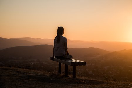 Woman sitting relaxing on a bench at sunset