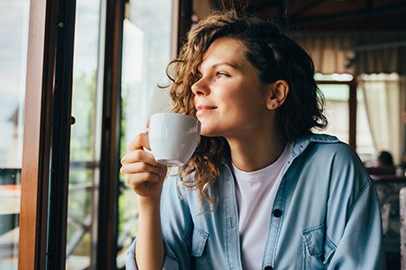 Smiling calm young woman drinking coffee