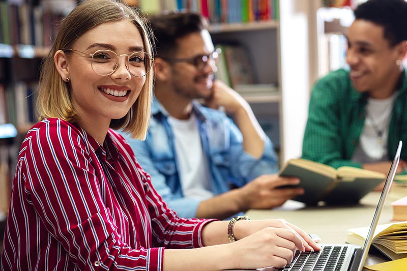 Smiling female student working at a laptop