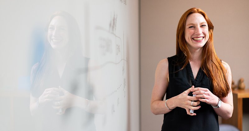 Smiling woman at work next to a whiteboard in a office