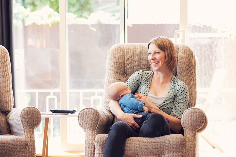 Suzi Hamilton sitting in a chair holding her baby