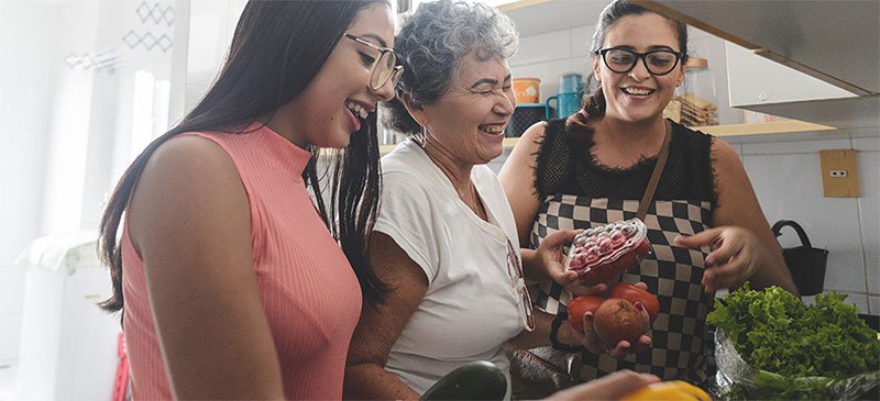 Three women smiling preparing a meal together