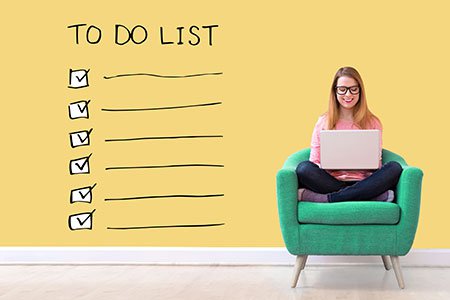 To do checklist on yellow wall with young woman using her laptop in a chair