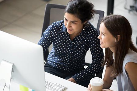 Two colleagues looking at laptop screen in office