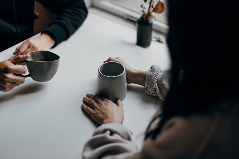 Two people holding coffees having a conversation