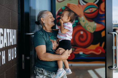 Māmā holding cute toddler in her arms