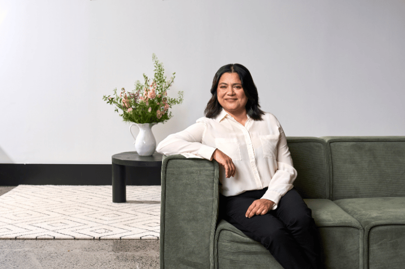 Dr Savitha sitting on a couch.