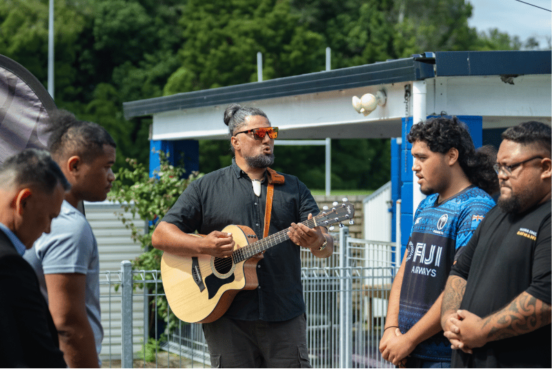 Man playing guitar, teens singing along