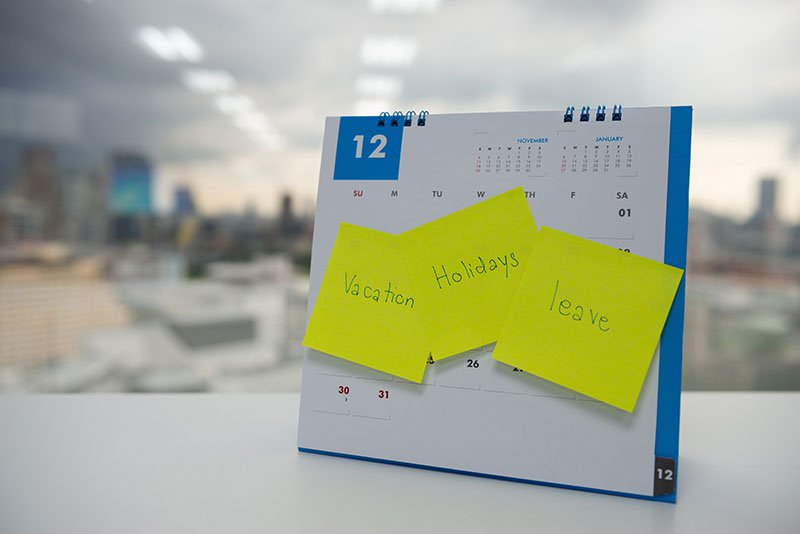 Vacation, holiday and leave on paper note stick on the calendar of December for year end holidays