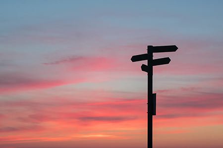 direction sign against a sunset