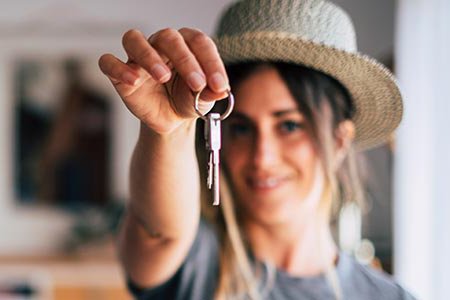 Woman holding keys to a house in her outstretched hand