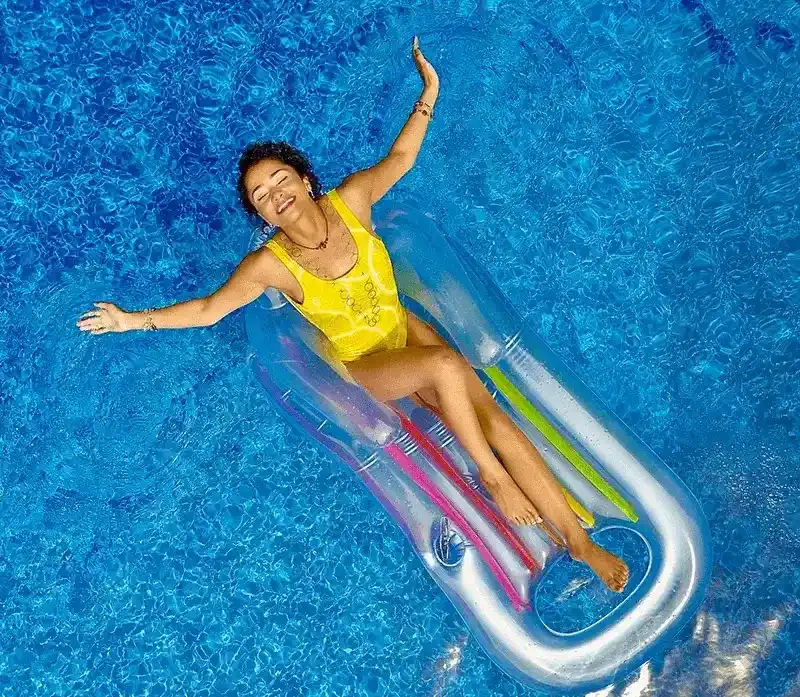 Woman in a yellow swimsuit lying on an inflatable pool chair in swimming pool