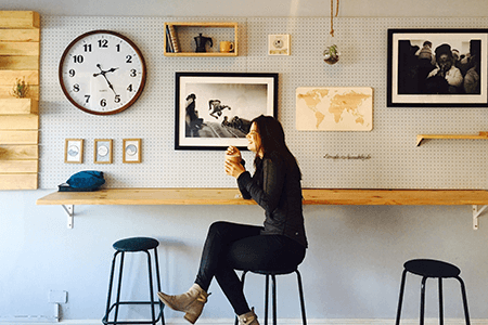 Woman-sitting-on-a-stool-at-a-cafe-enjoying-a-coffee-and-laughing