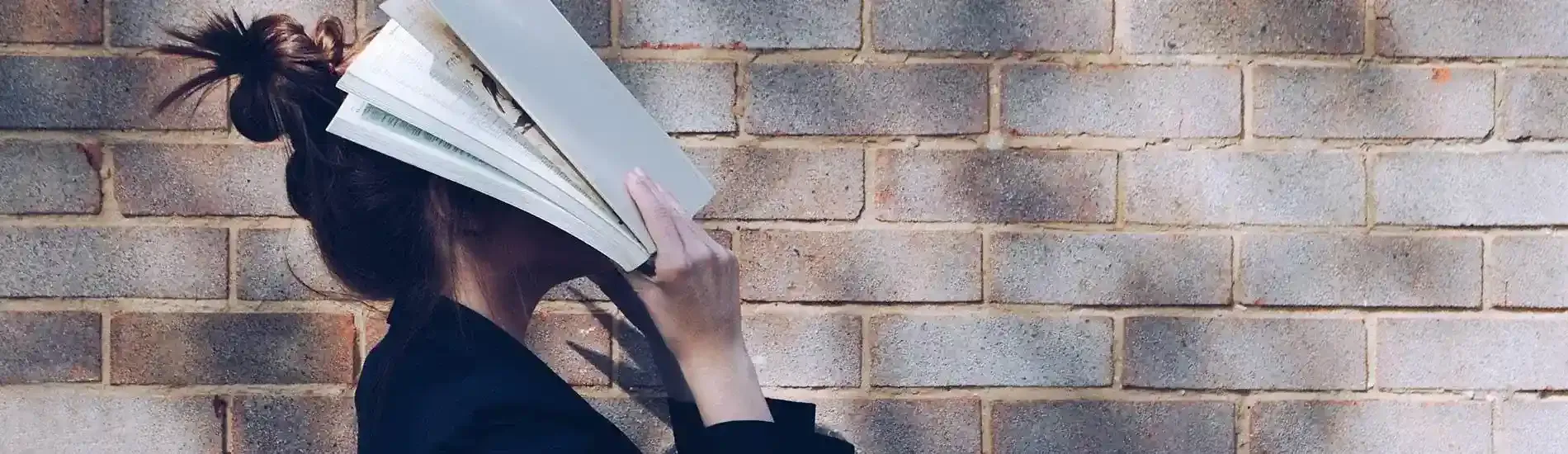 Woman with a book over her face stressed about exams