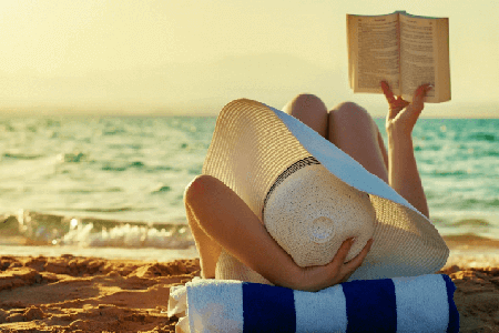 Woman-with-a-giant-sun-hat-reading-a-book-on-the-beach-relaxing-listing-image.png