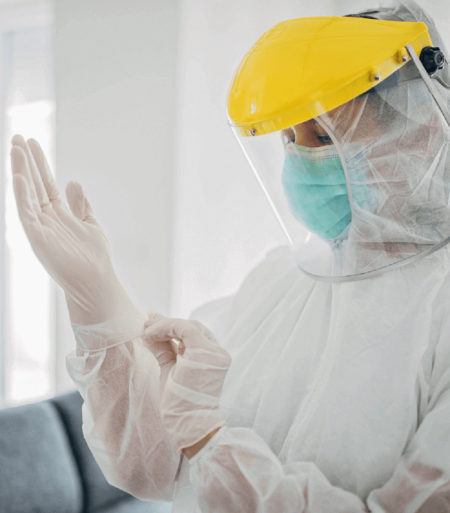 Woman wearing PPE putting glove on right hand