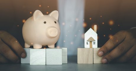 Young business man in suit holding home and piggy bank savings for buying home
