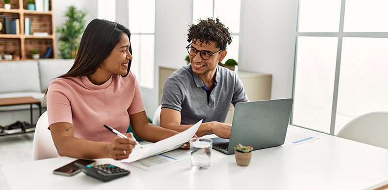 Young couple smiling at each other while working at their desks