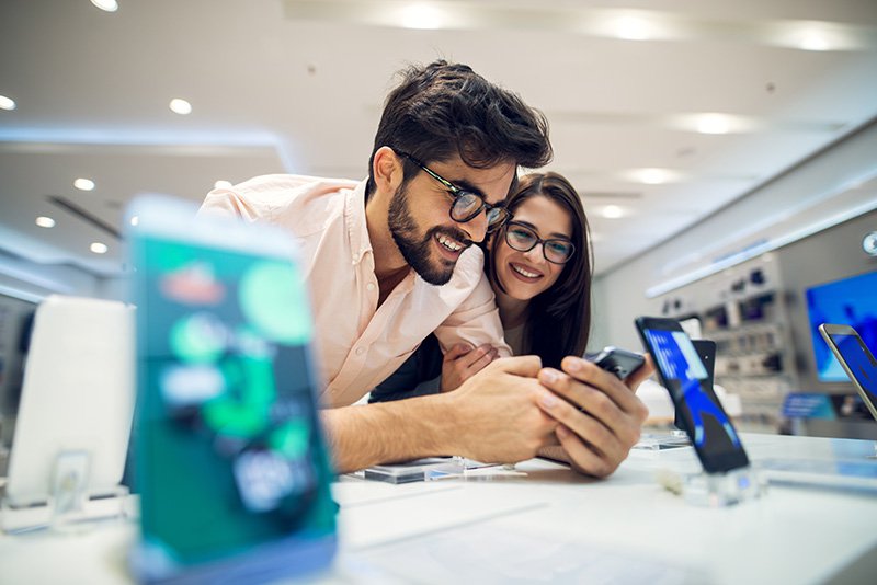 Young student couple choosing a new mobile in a tech store