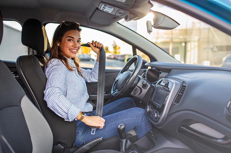 Young woman fastening her seatbelt in a car