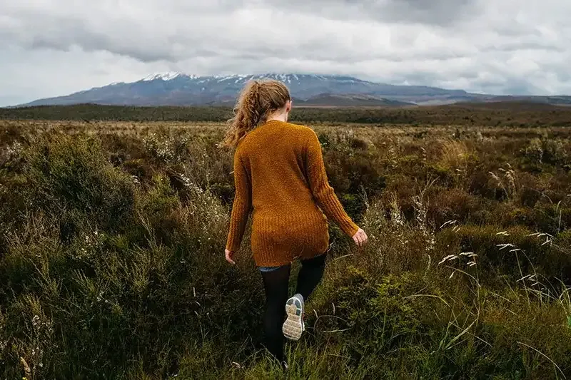 Young woman walking in field with mountain in the background