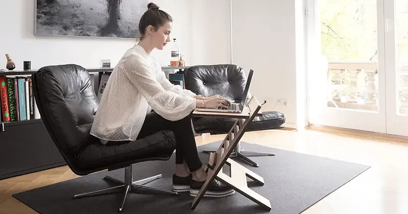 young woman working from home on her computer sitting at a flexible desk