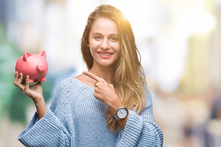 Young beautiful blonde woman holding piggy bank over isolated background very happy pointing with hand and finger