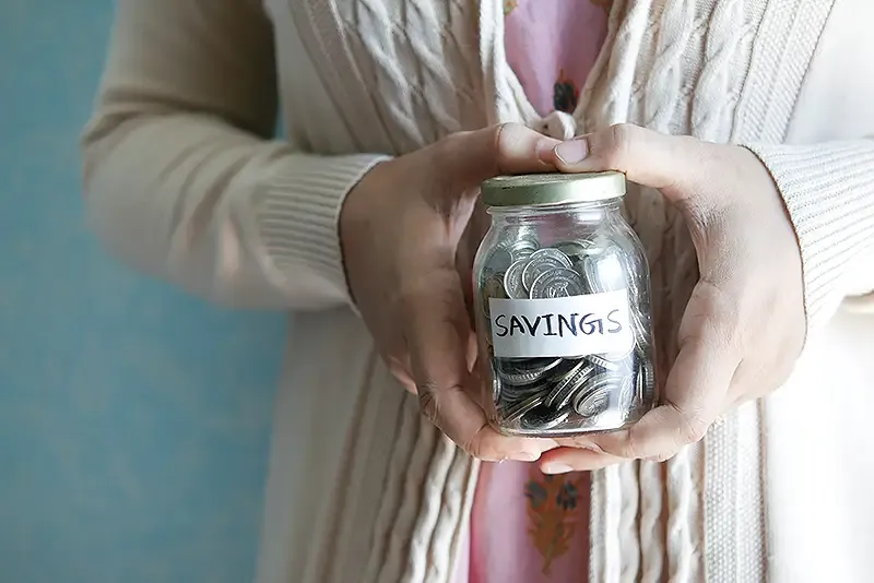 a retirement savings jar of coins being held by someone