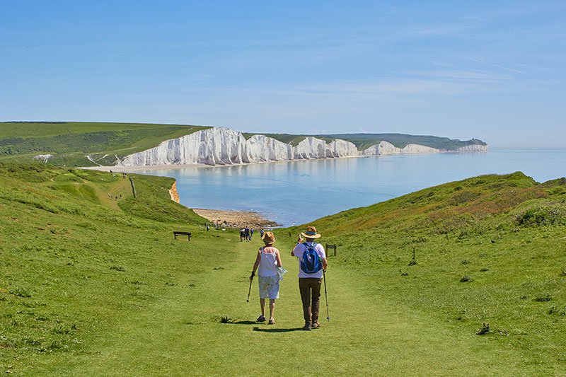 an older couple enjoying a walk on a hillside overlooking the ocean