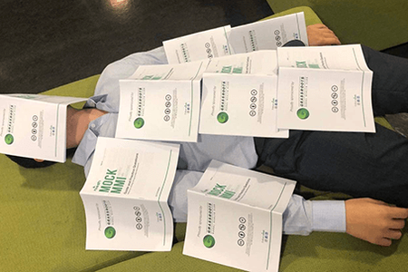 A person lays covered in fliers for Michaela Rektorysova's pre interview workshop