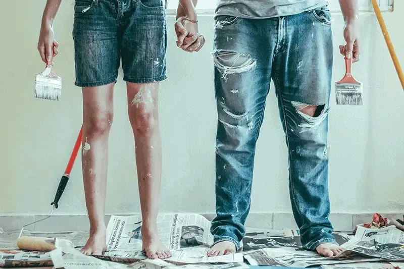 girl and guy holding hands with a paintbrush in their other hand