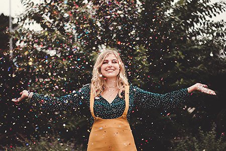 girl-standing-outside-throwing-confetti-in-the-air