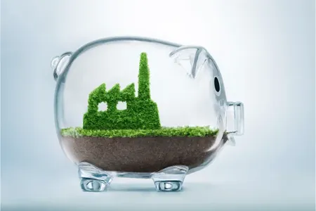 glass piggy bank with soil and trees growing inside in the shape of a building