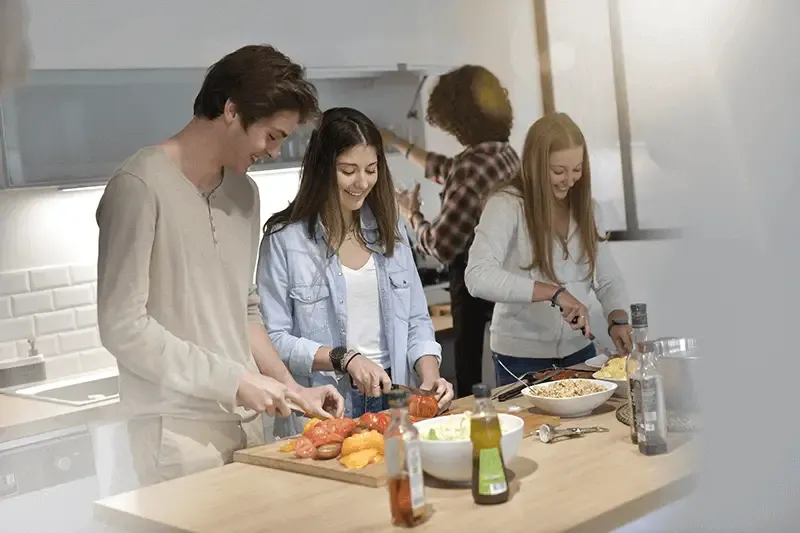 A group of friends happily cooking a meal together