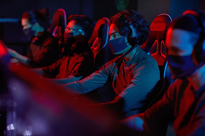 A group of hackers sitting at their computers wearing facemasks to protect against COVID-19